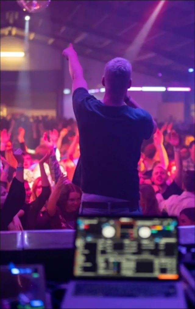 MAEZ zeigt mit dem Finger in die Luft, vor ihm eine volle Halle